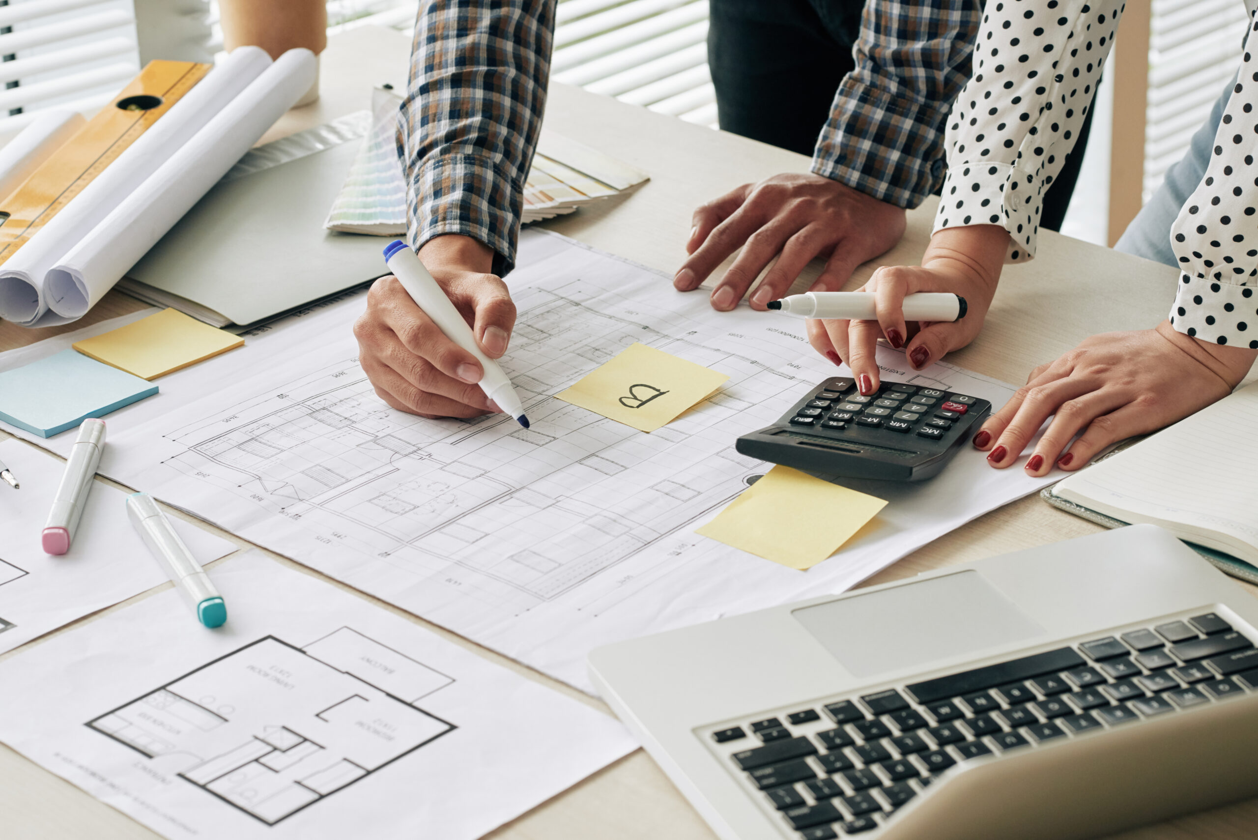 man and women looking over construction plans and using a calculator and markers